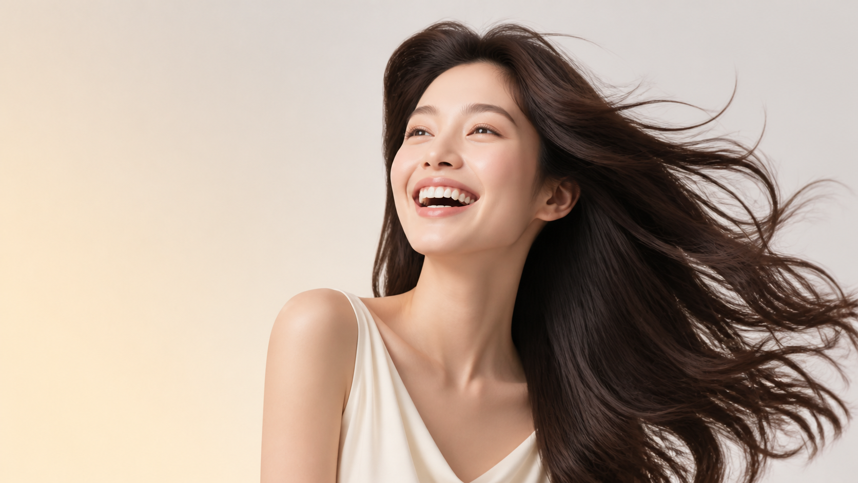 밝게 웃으며 바람에 풍성하게 흐르는 윤기 나는 머릿결을 보여주는 모델